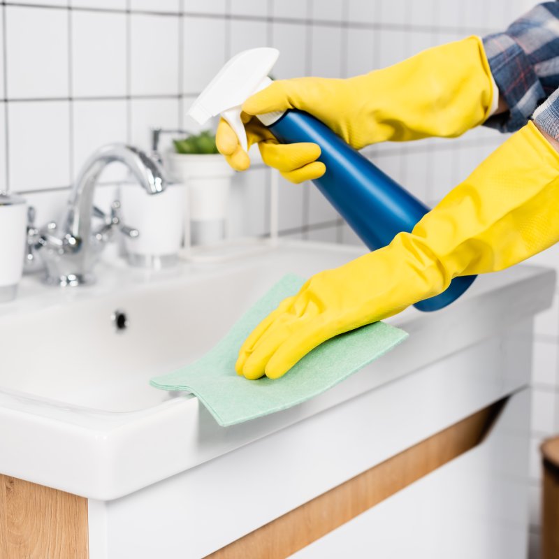 Cleaner wiping a bathroom sink during a deep clean.